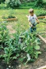 Ein kleiner Junge beim Gießen der Gemüsegärten — Stockfoto