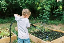 Маленький хлопчик робить свою справу поливу овочевих садів — стокове фото