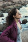 Красива жінка розмірковує про океан з фіолетовим дощовим пальто — стокове фото