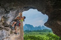 Joven escaladora escalando en zona remota en Yangshuo, China - foto de stock