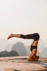 Young beautiful woman practicing yoga with mountain view in the background. — Stock Photo