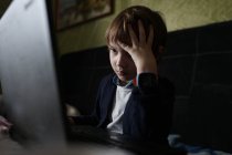 Сфокусированный ребенок сидит за компьютером — стоковое фото