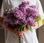 Молодий хлопчик тримає букет фіолетових бузкових квітів — стокове фото