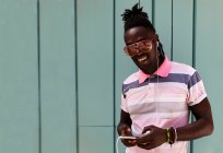 Jeune cubain avec des tresses afro connecté à son mobile — Photo de stock