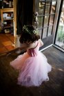 Молода дівчина крутиться біля вхідних дверей в навчальному посібнику та квітковій короні — стокове фото
