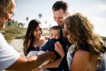 Família sorri como pai segura bebê na praia — Fotografia de Stock