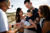 Famiglia sorride come papà tiene il bambino sulla spiaggia — Foto stock