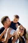 Papa hält & küsst Sohn, während Familie zusieht — Stockfoto