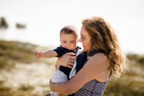 Grandmother Holding & Snuggling Grandson While Standing on Beach — Stock Photo