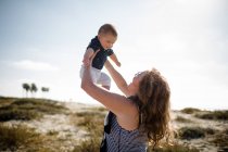 Grandmother Holding Grandson High While Standing on Beach — Stock Photo