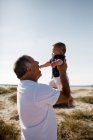 Nonno Holding nipote mentre in piedi sulla spiaggia — Foto stock