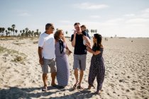 Familia de cinco caminando en la playa - foto de stock