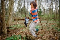 Un niño y una niña juegan en un bosque juntos la naturaleza en un día gris fresco - foto de stock