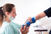 Infermiera rendendo un braccialetto ad una donna paziente — Foto stock