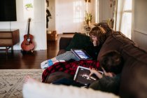 Young sister and brother using tablets at home on sick day — Stock Photo