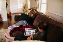 Junge Schwester und Bruder sehen Filme auf Tablets, während sie zu Hause krank sind — Stockfoto