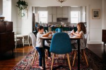 Маленькі діти, сидячи за обіднім столом, займаються мистецтвом та ремеслами разом — стокове фото