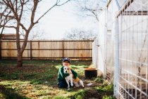 Junge lächelt und umarmt Hund im Hinterhof im Frühling — Stockfoto