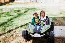 Menino e menina sentados em rodas motrizes sorrindo durante a primavera — Fotografia de Stock