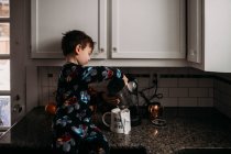 Giovane ragazzo versando il latte nella tazza di caffè — Foto stock