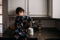 Junge schüttet Milch in Kaffeetasse — Stockfoto