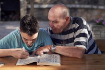 Boy and his grandfather making crosswords — Stock Photo
