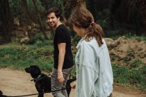 Young man looking back over shoulder at a woman while walking dogs — Stock Photo