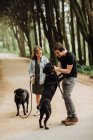 Jovem casal andando cães no parque — Fotografia de Stock