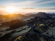 Прекрасный вид с воздуха на извилистую дорогу между скалистыми горами на фоне заката в Рейкьявике — стоковое фото