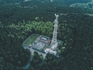 AERIAL: Drohnenschuss auf alte Funkturmstation im satten Grünen Wald, umgeben von Bäumen — Stockfoto