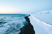 Inyección aérea aérea de hermosa playa negra en Islandia en invierno con cuartel general de nieve - foto de stock