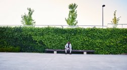 Afroamerikaner sitzt auf einer Parkbank. Er ist ein stattlicher Geschäftsmann. — Stockfoto