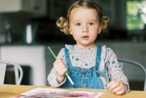 Ein kleines Mädchen malt mit Aquarellen an einem Tisch — Stockfoto