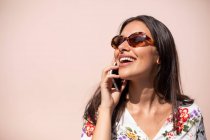 Mujer ejecutiva joven hablando por teléfono con fondo rosa - foto de stock