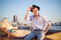 Smiling young boy with hat on the roof of a building — Stock Photo