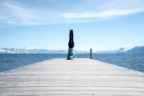 Woman does a headstand at the end of a pier in South Lake Tahoe, CA — Stock Photo
