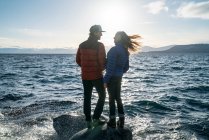 Молоде подружжя закоханих стоїть на скелі в озері Тахо взимку. — стокове фото