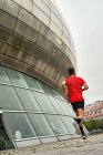 Jovem correndo em uma camisa vermelha e calças pretas através do parque — Fotografia de Stock