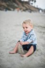 Маленький хлопчик грає з піском на пляжі Каліфорнії. — стокове фото