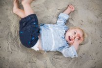 Niño jugando con arena en una playa de California - foto de stock