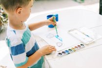 Little boy painting a car with watercolors outside on the patio — Stock Photo