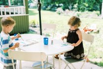 Two siblings painting with watercolors outside on the patio — Stock Photo