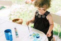 Toddler girl painting with watercolors outside on the patio — Stock Photo