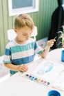 Five year old painting with watercolors outside on the patio — Stock Photo