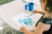 Petite fille peinture avec aquarelles à l'extérieur sur le patio — Photo de stock