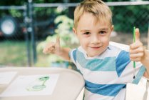 Маленький художник малює акварелями зовні на патіо — стокове фото