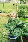 Хлопчик тримає в руках букет капусти в овочевому саду — стокове фото