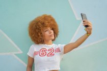 Mulher com cabelo afro tirar uma selfie com seu smartphone — Fotografia de Stock