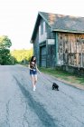 Девочка-подросток выгуливает щенка на поводке в поле — стоковое фото