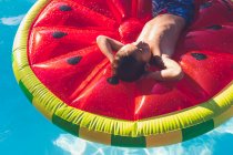 Garçon froid dans la piscine sur flotteur de pastèque — Photo de stock